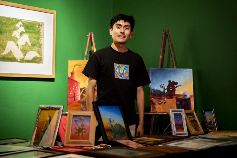 Artist proudly displaying his diverse paintings at Museo de las Americas, an exhibit curated for the museum.